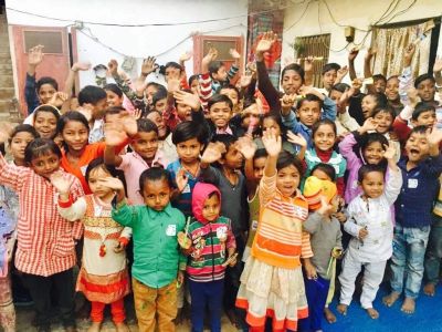 Group of children smiling and waving enthusiastically.